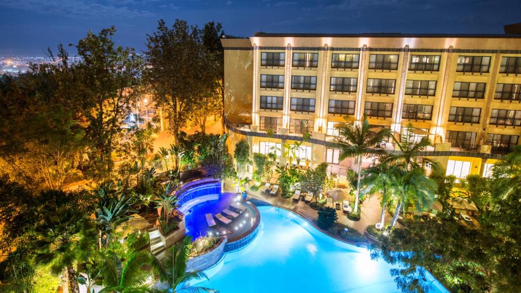 Luxe Kigali Serena Hotel bij nacht, omringd door palmen en zwembad – ideaal begin of einde van je reis met Christoffel Travel