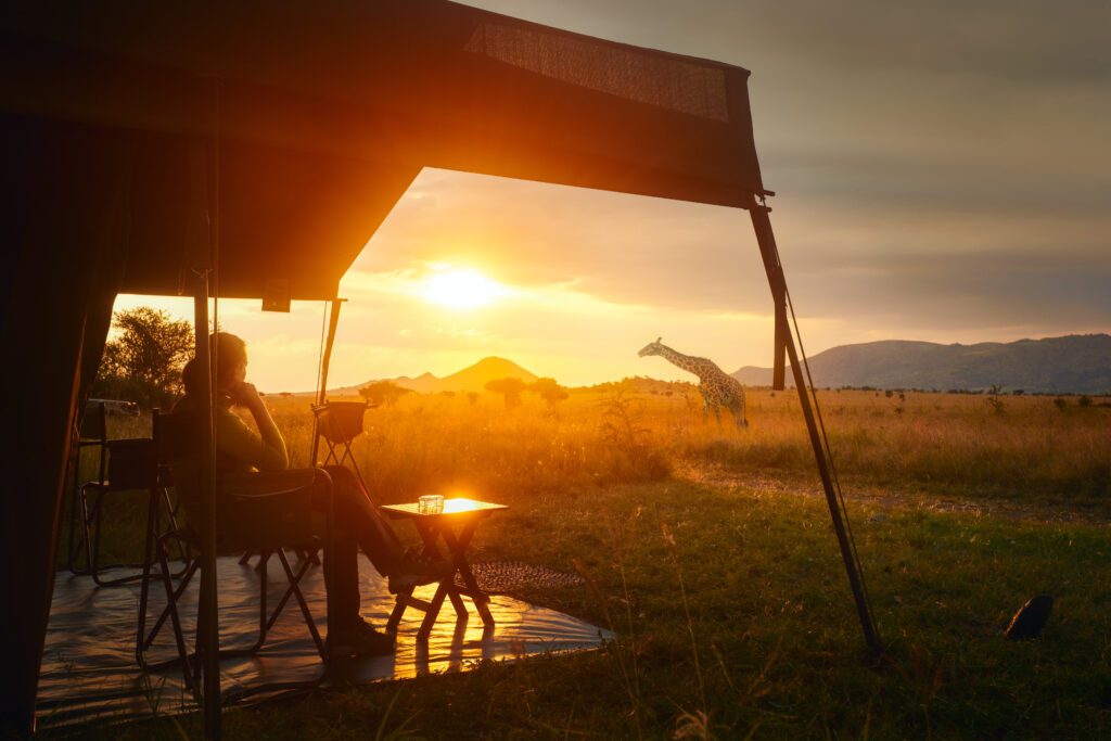 Vrouw ontspant bij luxe safaritent tijdens zonsondergang in de savanne van Serengeti National Park, Tanzania – Christoffel Travel