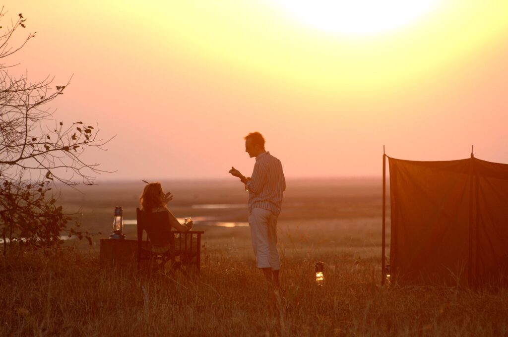 Glas wijn bij zonsondergang tijdens fly-camping in Katavi National Park – exclusieve safaribeleving met Christoffel Travel