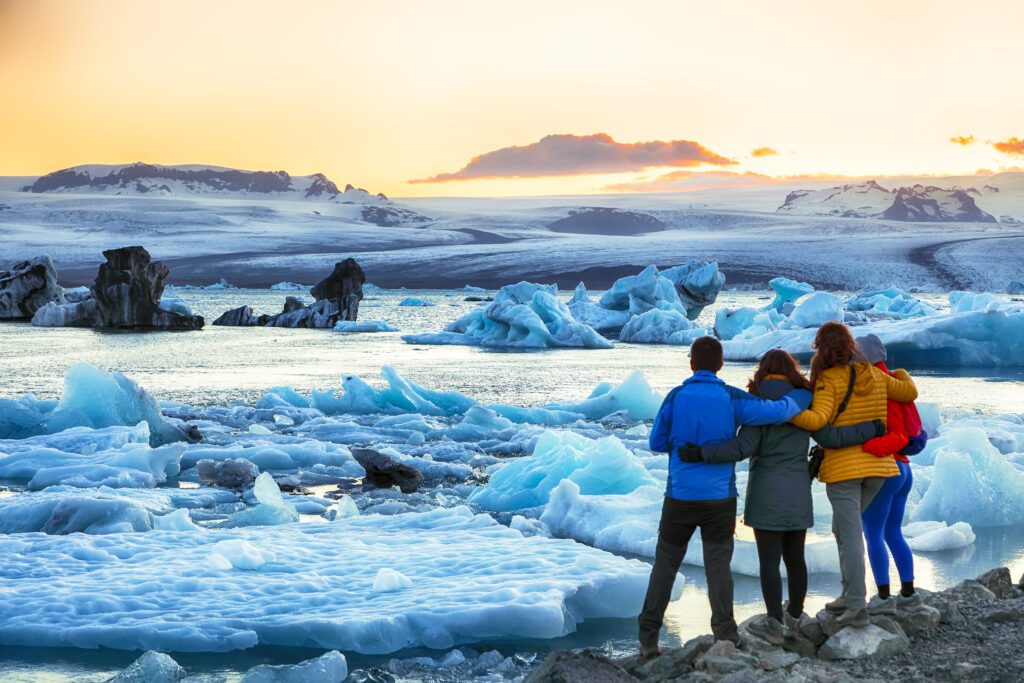 Groep bewondert drijvende ijsbergen in Jokulsarlon gletsjermeer bij zonsondergang, IJsland – incentive reis met Christoffel Travel.