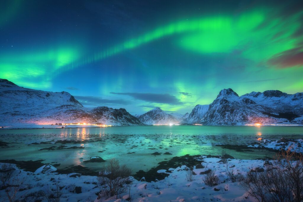 Noorderlicht boven de Lofoten met besneeuwde bergen en weerspiegeling in het water, Noorwegen – incentive reis met Christoffel Travel.