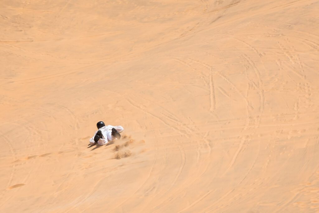 Avontuurlijke zandboarder glijdt van een hoge zandduin in Swakopmund – Christoffel Travel.